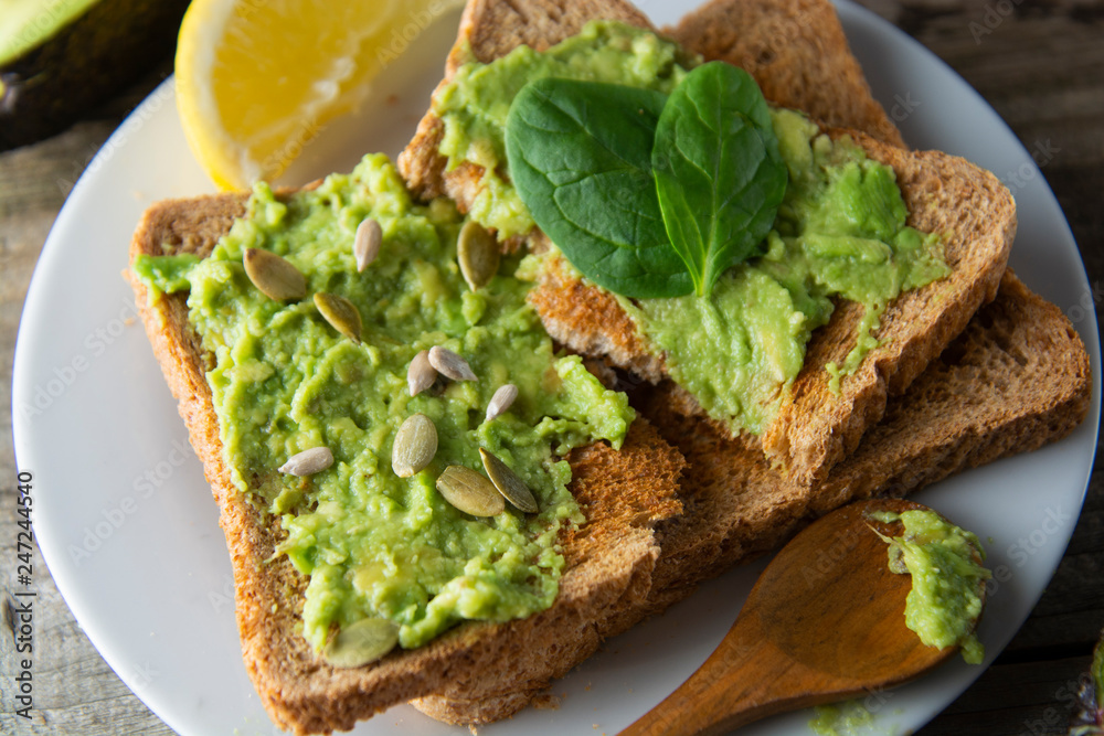 Delicious wholewheat toast with guacamole, avocado slices. Mexican cuisine. Healthy food, snack. Breakfast. Wooden rustic table.