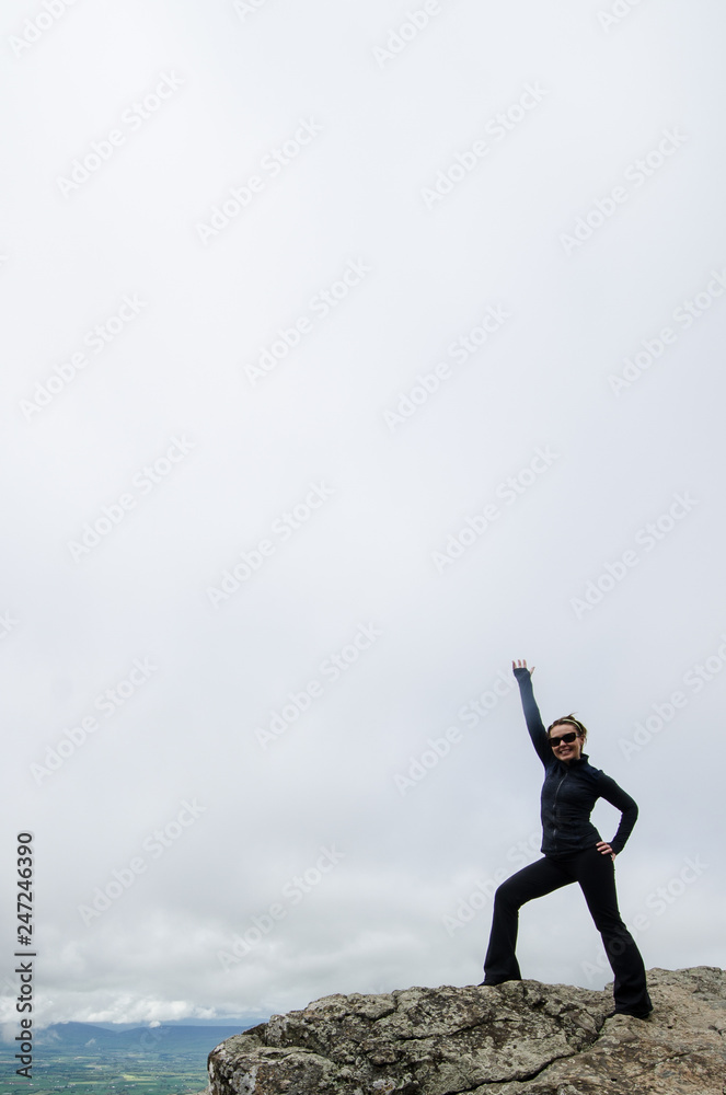 Accomplished smiling woman hiker poses at the summit of LIttle Stony Man, a hike in Shenandoah National Park in Virginia on a foggy day. Negative space, room for copy and text