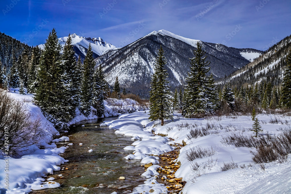 Mountain stream with fresh snow on sunny day