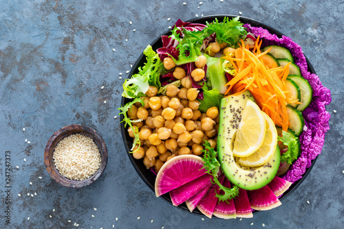 Salad Buddha bowl with fresh cucumber, avocado, watermelon radish, raw carrot, lettuce and chickpea for lunch. Healthy vegetarian food. Vegan vegetable dish. Top view