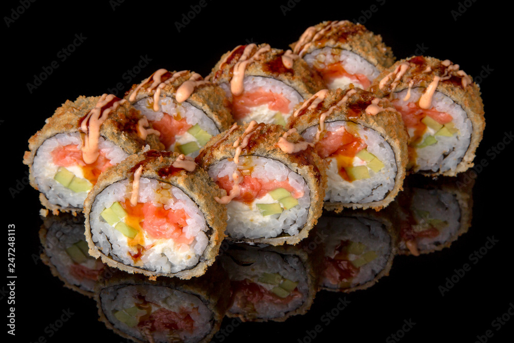 Hot fried Sushi Roll with smoked salmon, shrimp, avocado and cheese on black background. Sushi menu. Japanese food. Hot fried Sushi Roll with smoked salmon, shrimp, avocado and cheese on black background. Sushi menu. Japanese food.