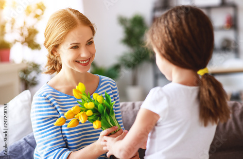 happy mother's day! child daughter   gives mother a bouquet of flowers to tulip and gift