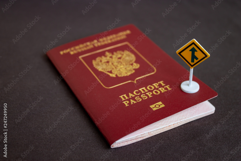 Russian international passport with a yellow arrow road sign - migration concept Russian international passport with a yellow arrow road sign - migration concept