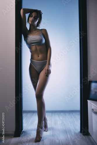 Fit woman wearing sport bra, standing in corridor, shallow depth of field