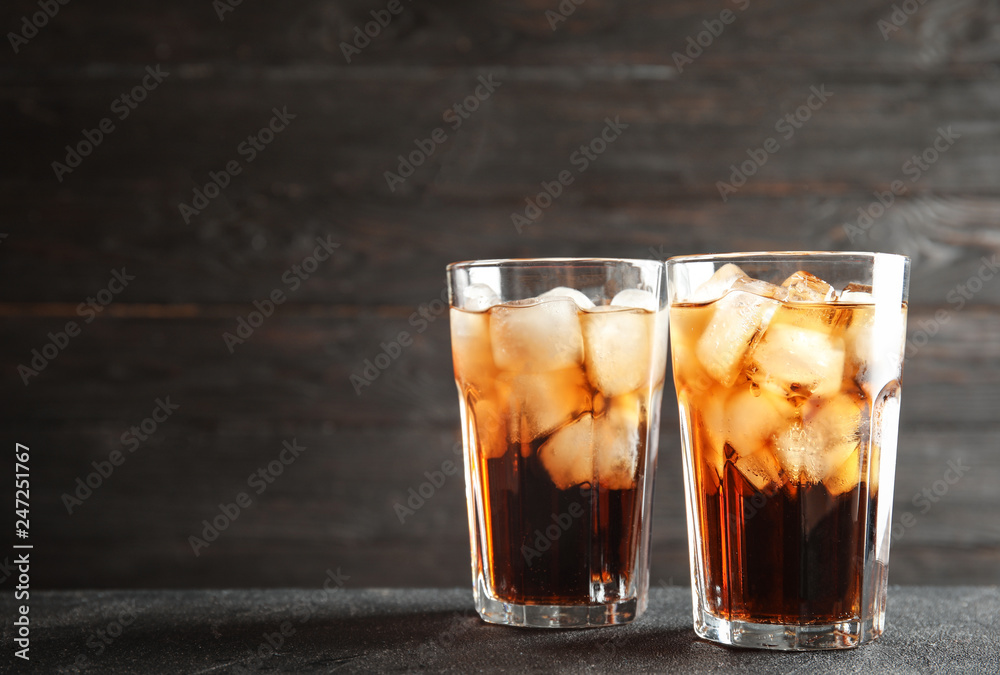 Glasses of refreshing cola with ice cubes on table. Space for text Glasses of refreshing cola with ice cubes on table. Space for text