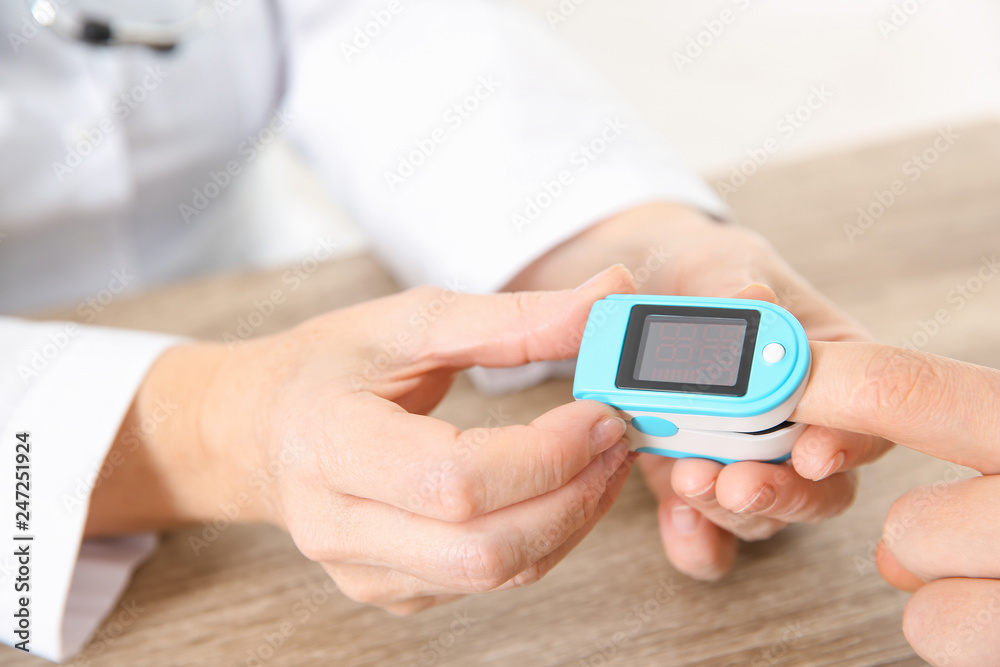 Doctor checking man's pulse with medical device in hospital, closeup Doctor checking man's pulse with medical device in hospital, closeup