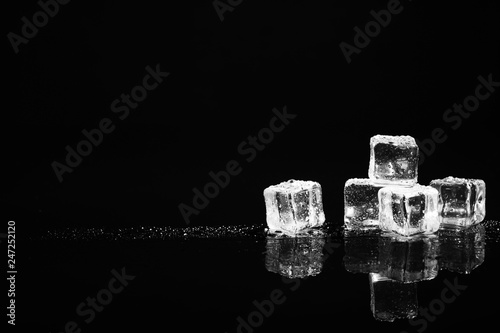 Pile of crystal clear ice cubes on black background. Space for text