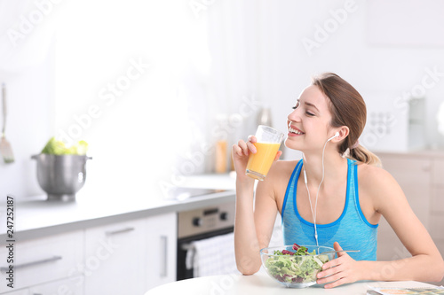 Young woman in fitness clothes having healthy breakfast at home. Space for text
