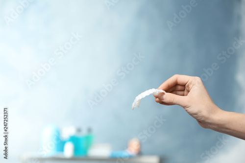 Dentist holding teeth cover in hand on blurred background. Space for text