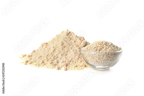 Pile of fresh flour and bowl with sesame seeds isolated on white
