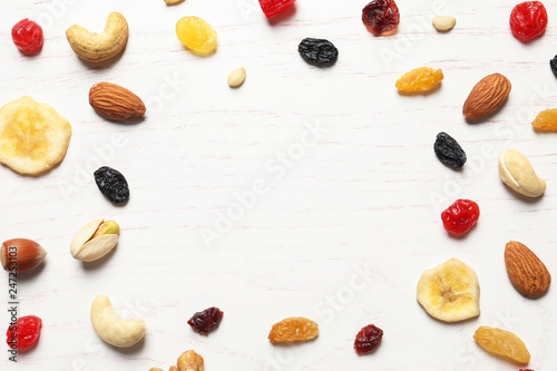 Flat lay composition of different dried fruits and nuts on wooden background. Space for text