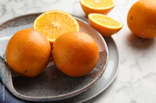 Plate with fresh juicy oranges on marble table