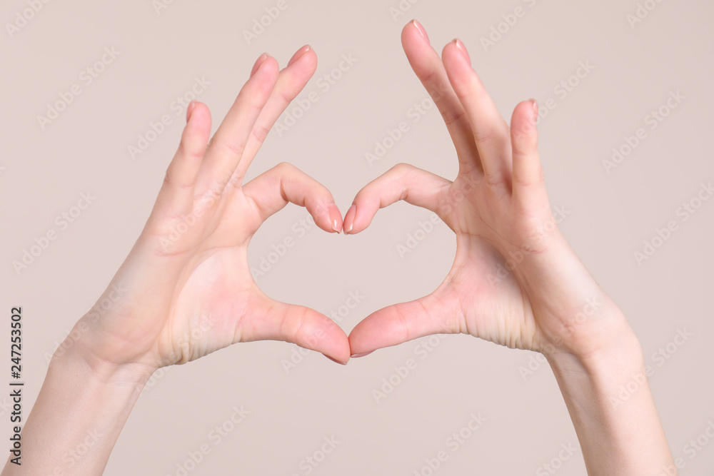 Obraz premium Young woman making heart with her hands on color background, closeup