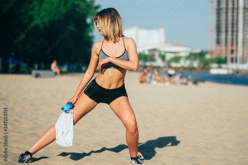 Blonde beautiful girl very sexy pose for camera in a public beach after  training with sporty look Stock-Foto | Adobe Stock