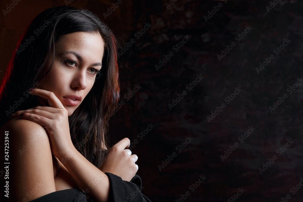 Closeup portrait of seductive model with naked shoulders, posing with red light. Space for text