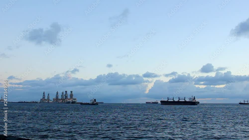 Cargo boat heading to Las Palmas harbor at sunrise in Canary Islands. Freight transportation sailing at dawn passing by big ships in Gran Canaria, Spain Cargo boat heading to Las Palmas harbor at sunrise in Canary Islands. Freight transportation sailing at dawn passing by big ships in Gran Canaria, Spain