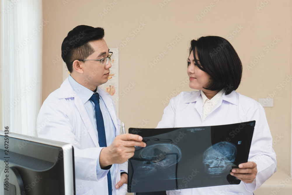 expertise doctor planning treatment for medical concept. Two asian doctor looking at film x-ray head of patient and discussing surgery plan for cure disease.