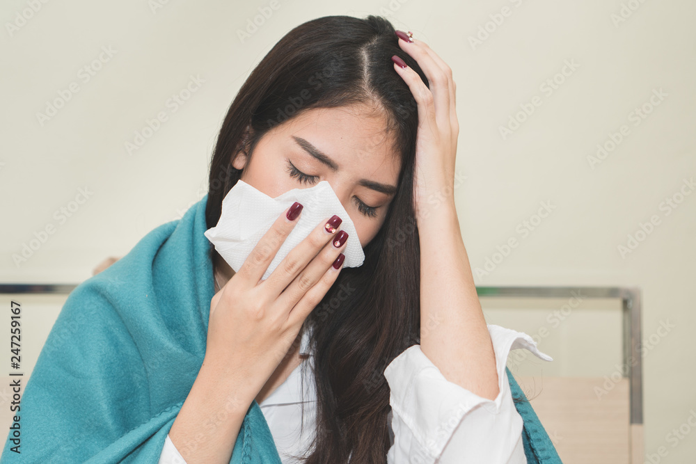 asian woman sneeze on the bed. unhealthy young female have cold and high temperature from fever and sitting on the bed.