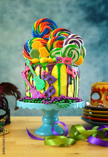 Mardi Gras theme on-trend candyland fantasy drip cake on colorful party table setting.