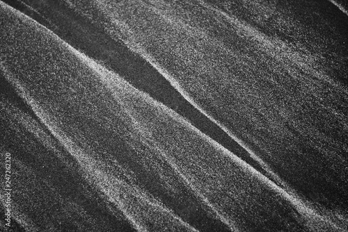Abstract patterns made by waves on famous black sand of New Zealand beaches. 