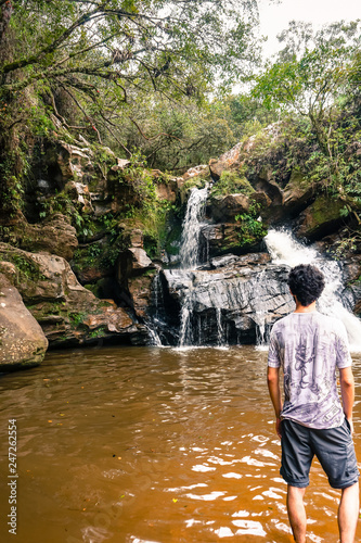 Man contemplating the Eubiose Waterfall in its natural pool. São Thomé das Letras, Minas Gerais, Brazil photo