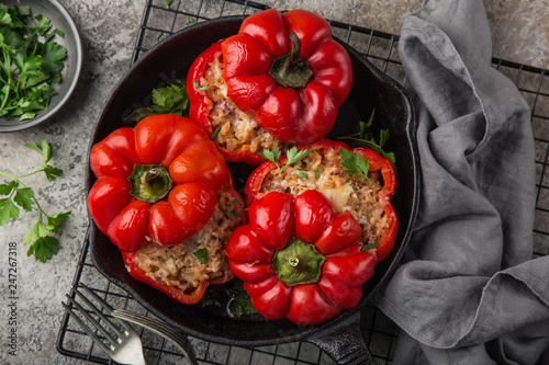 red bell peppers stuffed with meat, rice and vegetables on cast iron pan photo