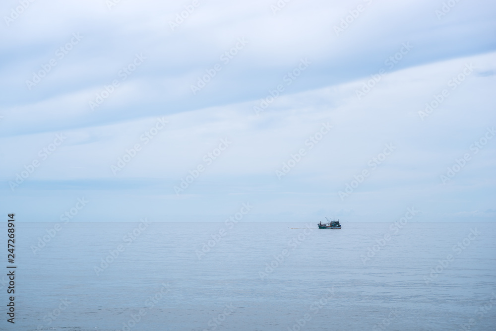 Fishing boat in the calm sea ocean and blue clear sky background. Gently blue and aquamarine colors.