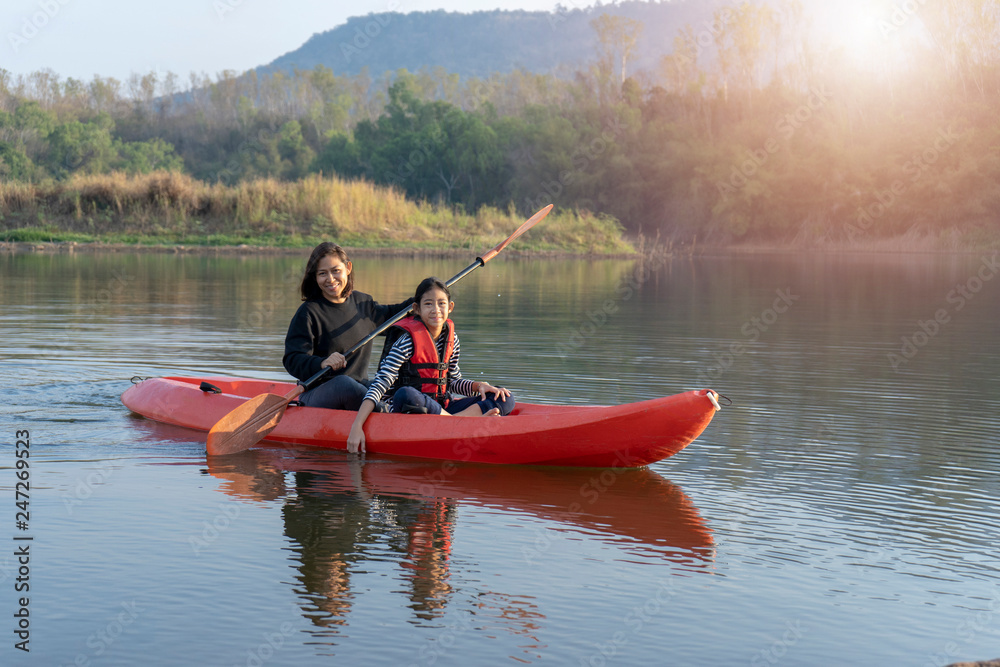 Mother and daughter rowing boat on calm waters Mother and daughter rowing boat on calm waters