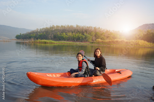 Mother and daughter rowing boat on calm waters
