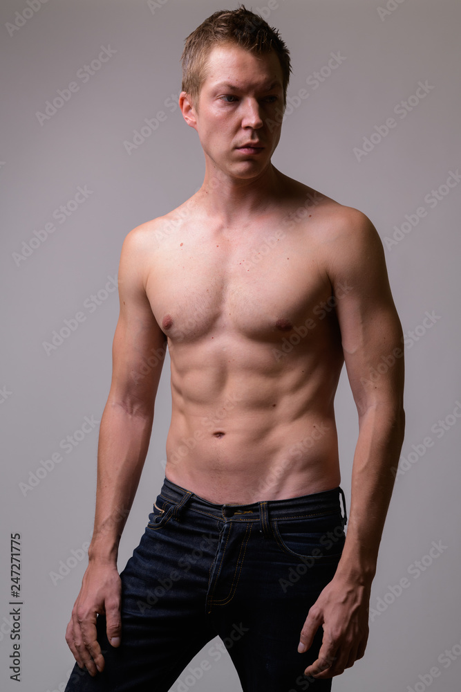 Studio shot of young handsome muscular shirtless man thinking