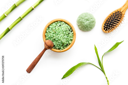 Asian spa treatment concept with natural ingredients. Spa salt, lotion, sponge near bamboo on white background top view pattern