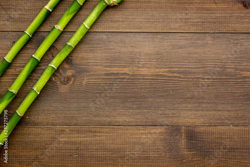 Fototapeta Naklejka Na Ścianę i Meble -  Asian background. Green bamboo branches on dark wooden background top view copy space