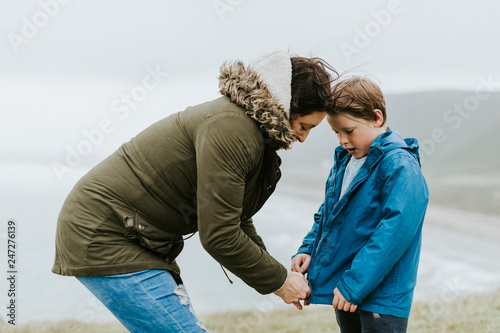 Fotografie Mother helping her son zip his jacket