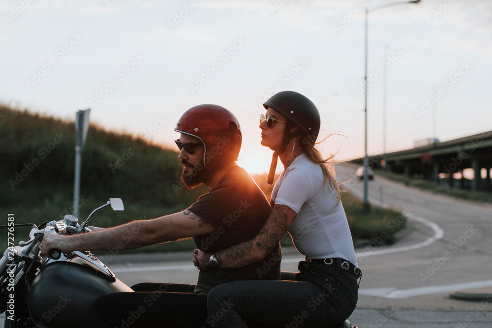 Obraz premium Para rowerzystów, jazda w dół drogi o zachodzie słońca