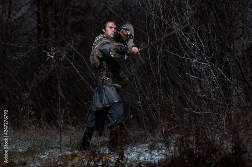 Medieval knight with sword in armor as style Game of Thrones in Winter Forest Landscapes