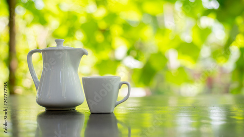 Fototapeta Naklejka Na Ścianę i Meble -  white cup of tea and pot on wooden table in garden