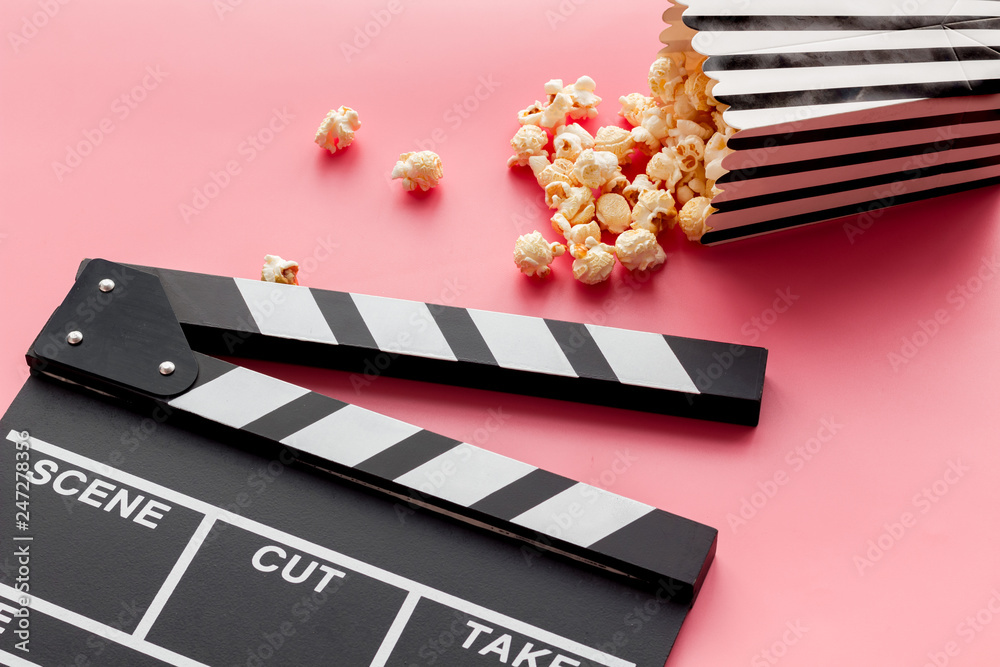 Film watching concept. Clapperboard and popcorn on pink background copy space