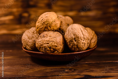 Ceramic plate with walnuts on a wooden table