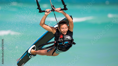 Photography Smiling girl performs a raley jump on a kiteboard