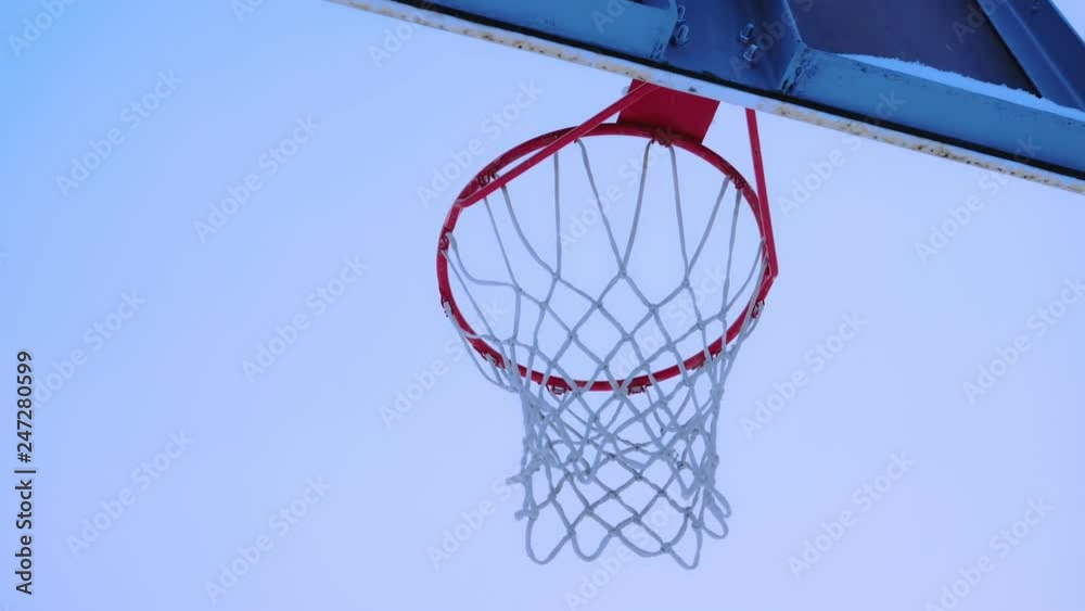 Basketball ball flies into the basket in the winter. It's snowing outside. Basketball ball flies into the basket in the winter. It's snowing outside.
