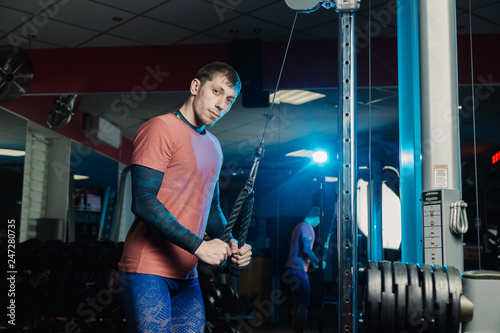 Handsome athletic man trains triceps on the block in the gym.