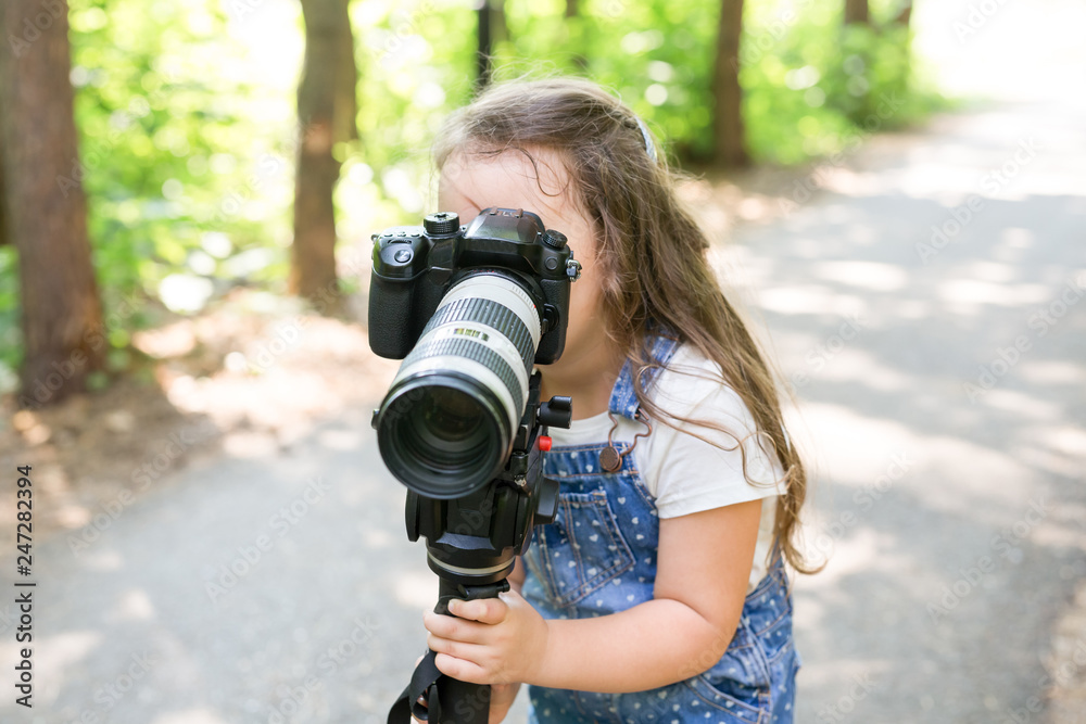 Hobby, profession, children and photographer concept - child with camera in forest Hobby, profession, children and photographer concept - child with camera in forest