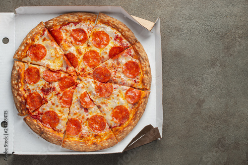 Tasty pepperoni pizza in a box on brown concrete background. Top view of hot pepperoni pizza. With copy space for text. Flat lay