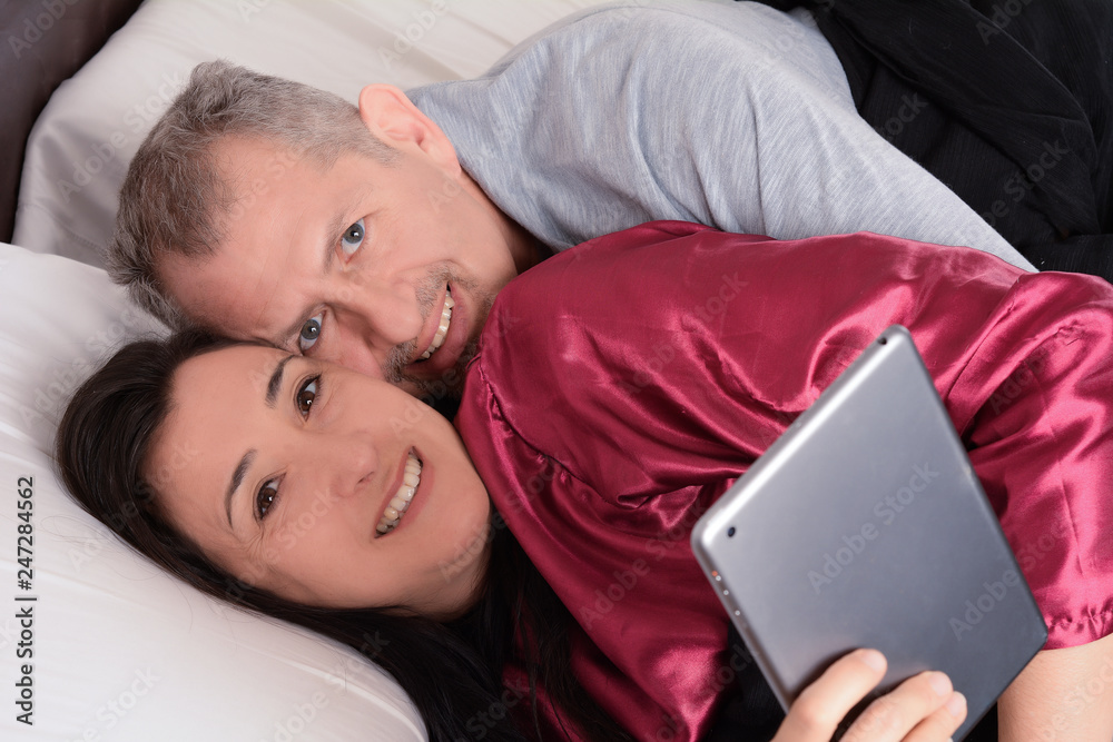 Happy middle-aged couple watching video on tablet at home Happy middle-aged couple watching video on tablet at home