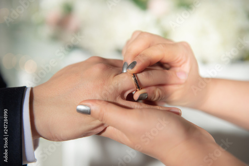 Wedding theme, Bride putting ring on groom hand, and they holding hands with a nice manicure neat. Close up hands of man and woman put wedding ring on hand.
