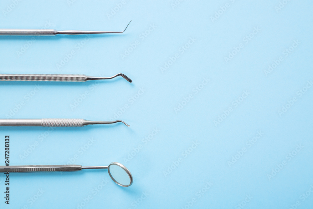 Dentist tools. Professional steel dental instruments with a mirror on light blue background with free space. Dental health and teethcare concept. Dentist tools. Professional steel dental instruments with a mirror on light blue background with free space. Dental health and teethcare concept.