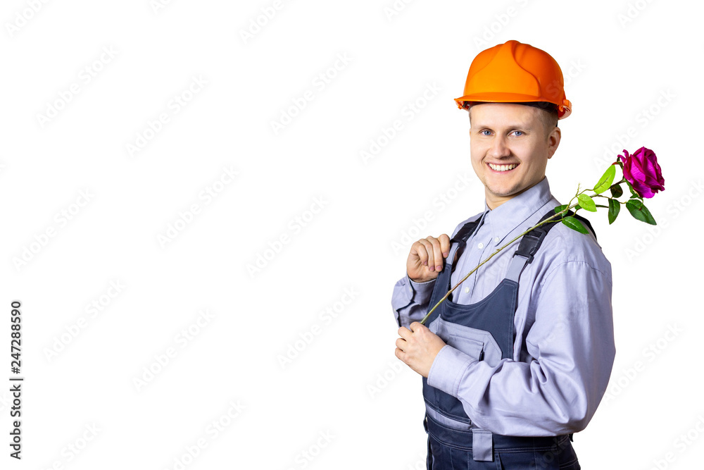 A cheerful smiling man builder on a white background with a rose in his hands congratulates everyone on the holiday. World Women's Day, March 8, the day of celebration, anniversary, holiday. Isolated