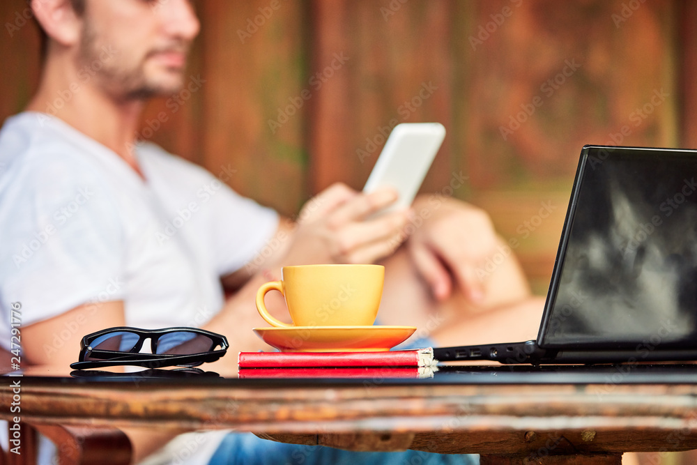 Man with smartphone, coffee / tea and laptop on a home porch. Man with smartphone, coffee / tea and laptop on a home porch.