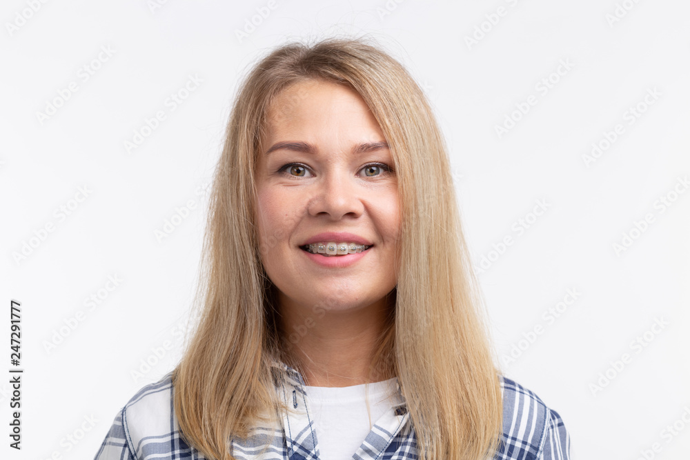 Teeth health, dentistry and bite correction - Happy smiling woman with braces on white background Teeth health, dentistry and bite correction - Happy smiling woman with braces on white background