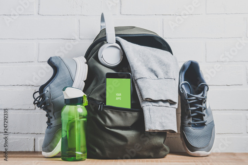 Green backpack with sportswear and sneakers. The concept of fitness or running